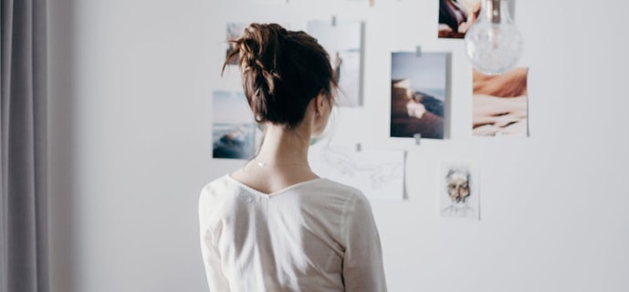 tablet image of woman looking at inspiration ideas on paper that 
        are stuck to the wall with triple-image